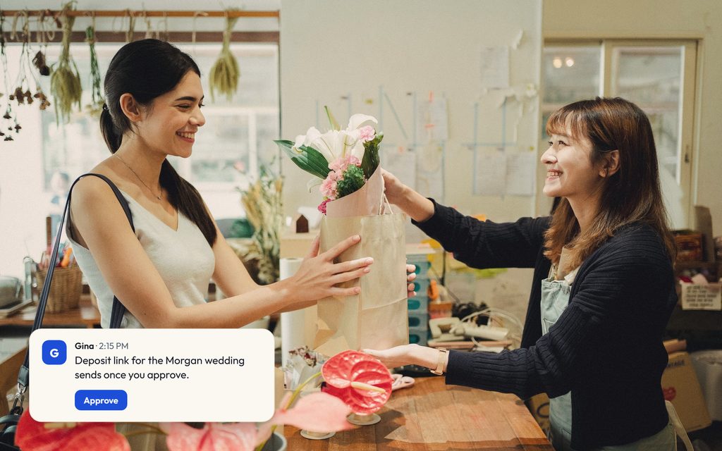 Florist handing a wrapped bouquet across the counter to a smiling customer, with a Gina message holding a deposit link until it's approved.